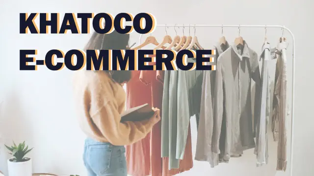 Khatoco E-commerce: a shopper holding a phone while browsing shirts on a clothing rail