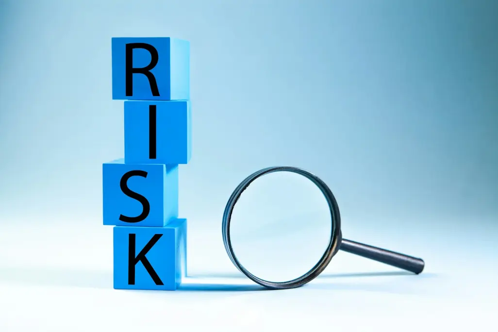 Blue blocks spelling out the word RISK next to a magnifying glass